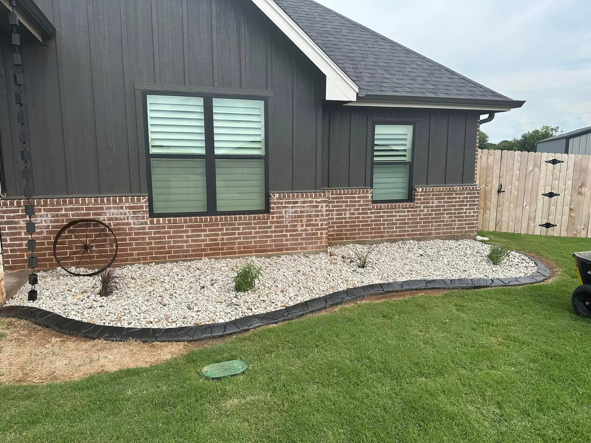 Curved river-rock landscape bed beside a dark home